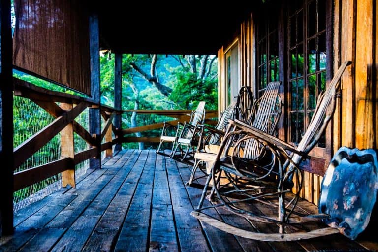 Rustic themed farmhouse inspired front porch with wooden inspiration from wooden chairs to wooden deck, 51 Farmhouse Porch Ideas
