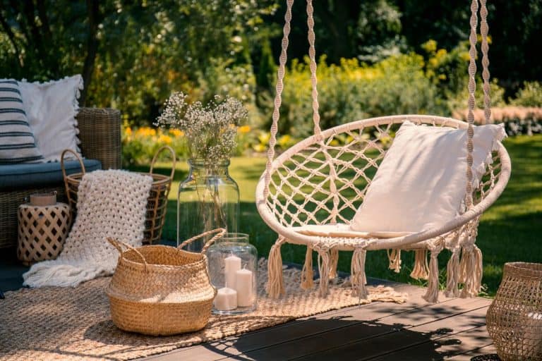 一个米色的绳子秋千挂在一个放松区，秋千上放着一个枕头，18 Front Porch Furniture Ideas