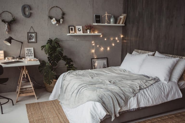 A bedroom with white bedding sets, small Christmas light on the side and a wallpaper pattern on the background, 13 Bedroom Decor Gift Ideas that You'll Love