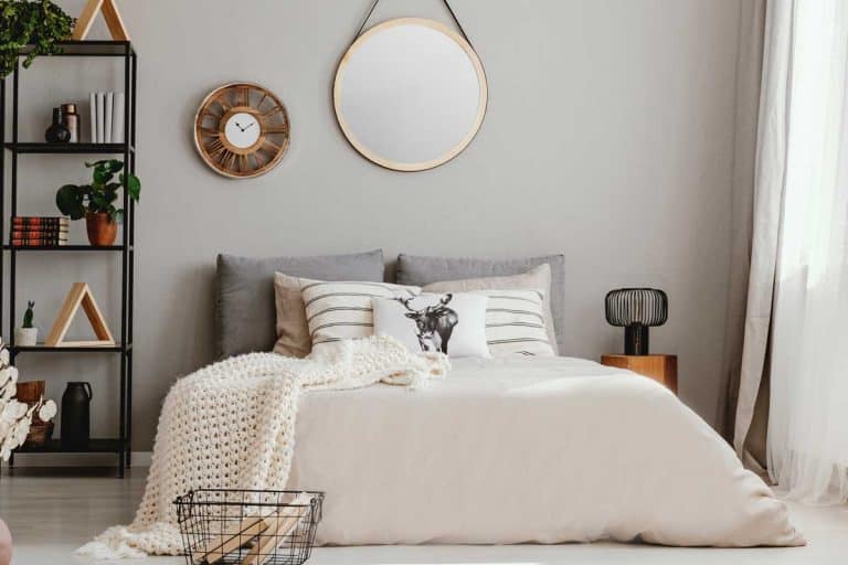 Bright bedroom interior in spacious modern apartment with beige design and round mirror above bed, Should I Put A Mirror Above My Bed?