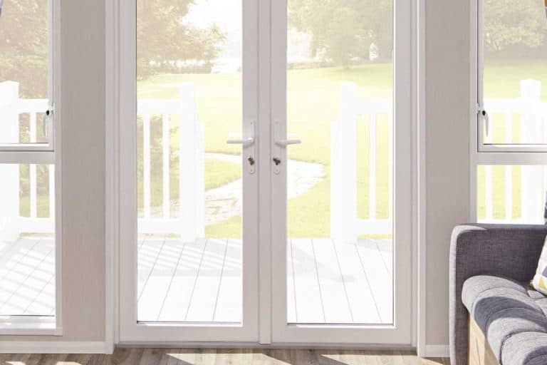 一扇通往客厅的白色法式门，可以看到前院的景色，How to Hang Roman Shades on french Doors[5步]