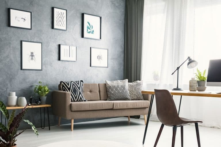 Bright home office interior with a sofa, graphics, desk with a computer, lamp and modern clock, Should Pillows And Curtains Match?
