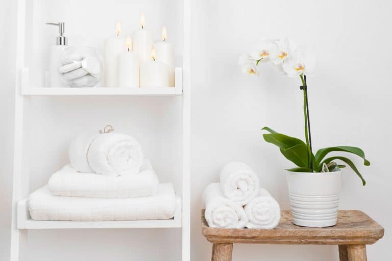 A shelf with clean towels next to a wooden table, How To Properly Fold Towels (5 Ways You Should Know)