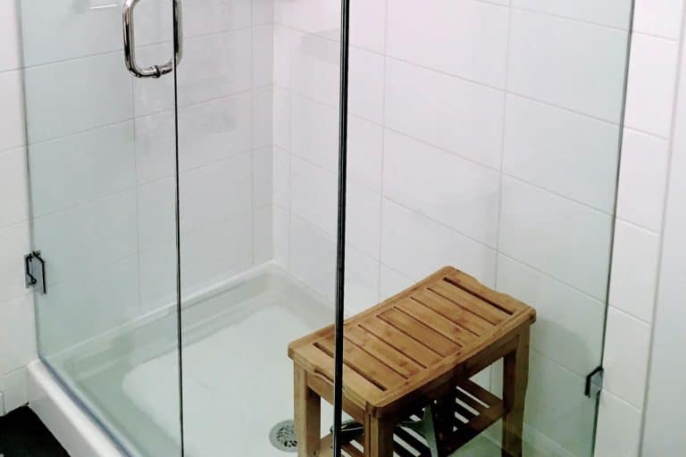 A small glass walled shower area with wooden shower bench, How Big Does A Shower Need To Be To Have A Bench?