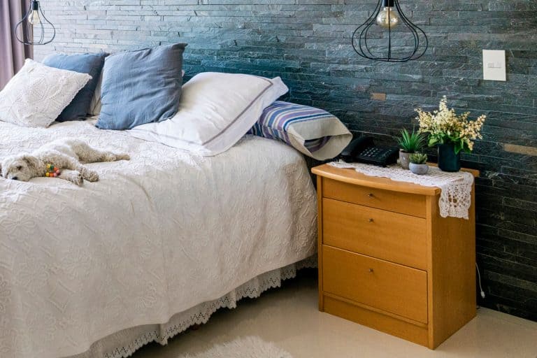 White dog relaxing on bed at home with bedside table, How Tall And Wide Should A Bedside Table Be