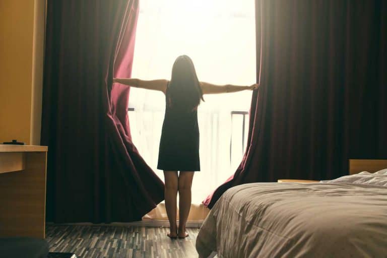 女士打开卧室窗户上的遮光窗帘，如何挂遮光窗帘[6步]