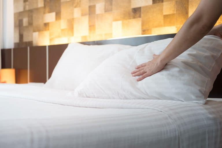 女人的手设置白色枕头在床上,怎么做To Spot Clean A Pillow