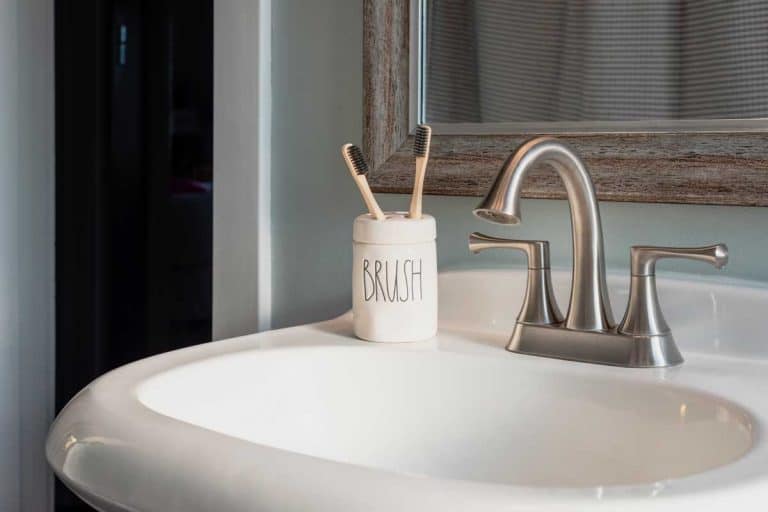 A bamboo toothbrushes in a ceramic holder on bathroom sink, 27 Awesome Bathroom Sink Ideas You Need To See