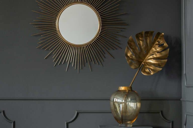 Decorative mirror above a golden plant leaf in a dark luxurious apartment interior, 11 