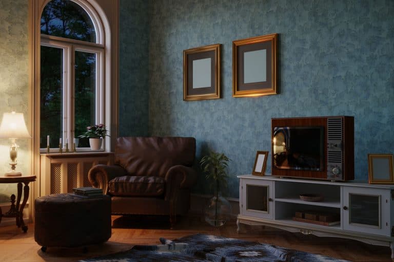 Interior of a small living room with a blue floral wallpaper, brown sofa, and an arched window, 11 Fun Wallpaper Ideas For Living Room Feature Wall