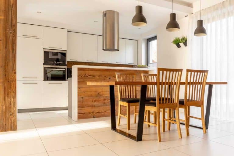 Spacious, open kitchen and dining room with wooden table and chairs, large window, white cupboards and tiles on the floor, What Color Cabinets Go With White Tile Floor?