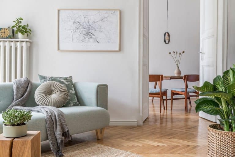 A Scandinavian themed living room with white painted walls, pastel colored couch, and an indoor plant on the side, How To Hang Pictures On Vaulted Ceiling Walls