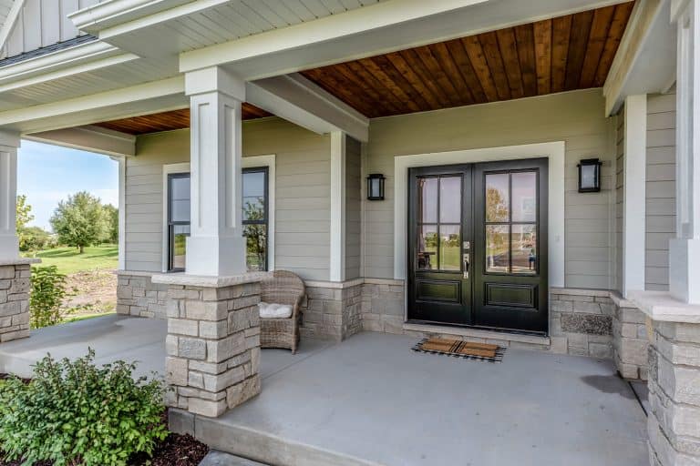 Front porch of a contemporary inspired house with gray painted wooden siding and stained tongue and groove ceiling, 11 Porch Ceiling Ideas That You'll Love