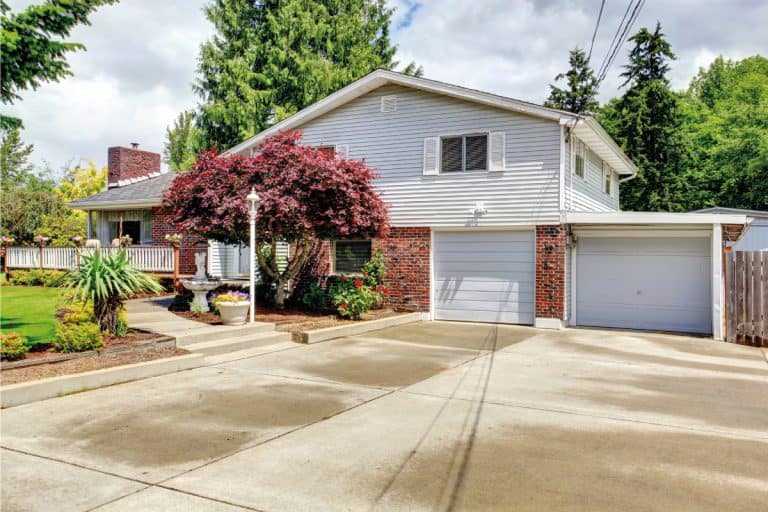 House-exterior-with-brick-wall-trim-and-concrete-pavement-driveway.-How-Often-To-Seal-A-Driveway-By-Surface-Type, How Often To Seal A Driveway By Surface Type