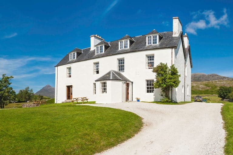 Large family home set in idyllic rural landscape below blue summer skies with large gravel driveway, 5 Ways To Keep Weeds From Growing In A Gravel Driveway