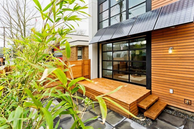 Modern contemporary house with wooden sidings and a small deck skirting area next to the huge windows, 8 Deck Skirting Ideas To Consider