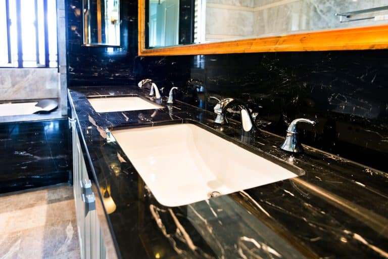A rustic designed vanity inside an earthy bathroom with a huge mirror, Does A Double Sink Vanity Share The Same Drain?
