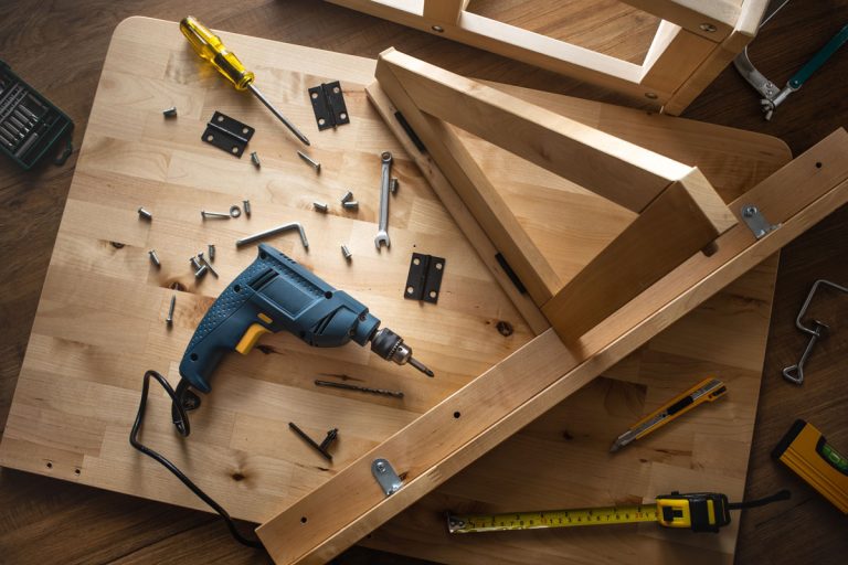 Top view of drill tool and another equipment on wood table furniture.assembly, improvement or repairing home interior concepts ideas, How To Brace A Wobbly Table?