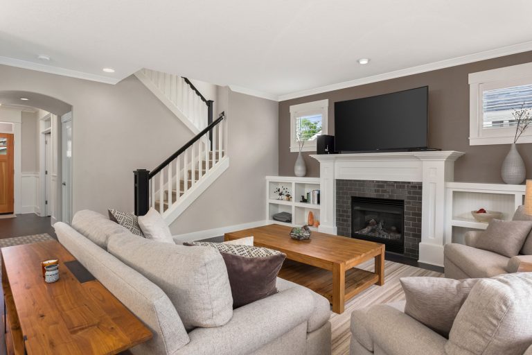 Gray and white living room with wooden furniture's and wooden flooring and a fireplace with TV on top, How To Arrange Living Room Furniture With TV
