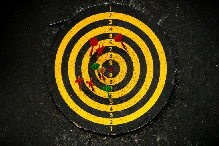 An old yellow dart board with holes hanged on black wall, How To Fix Dart Holes In A Wall Or A Door