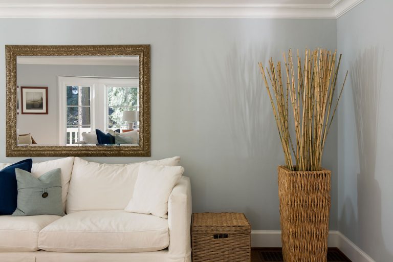 Living room interior with white couch and basket with a bamboo plant and a big mirror on the wall, How To Hang A Heavy Mirror On Drywall