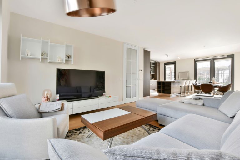 Luxurious living room in luxury apartment With gray spacious sofa and armchair, Should TV Stand Be Wider Or Longer Than TV?