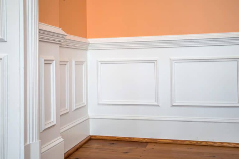 white wainscoting and chair rail on wall of orange peach dining living room of colorful home house - How High Should Wainscoting Be