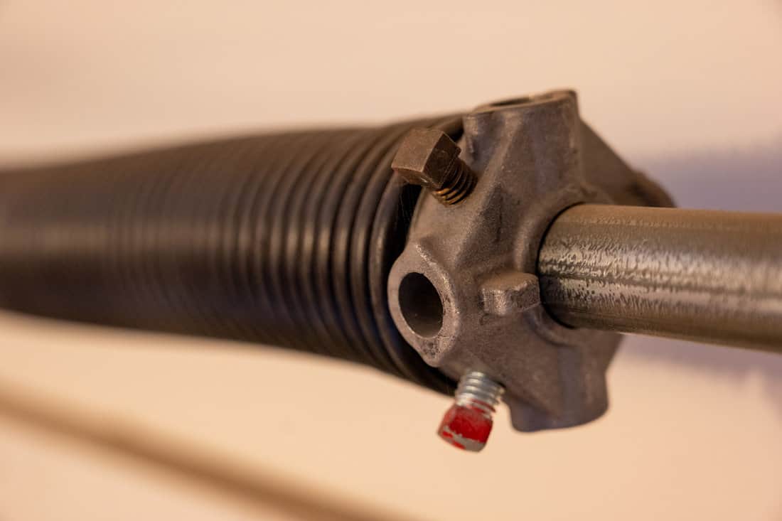 Close up side view of garage door coiled spring