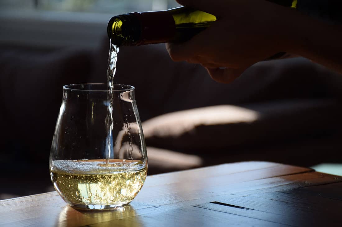 白葡萄酒被倒入一个无茎的葡萄酒杯中