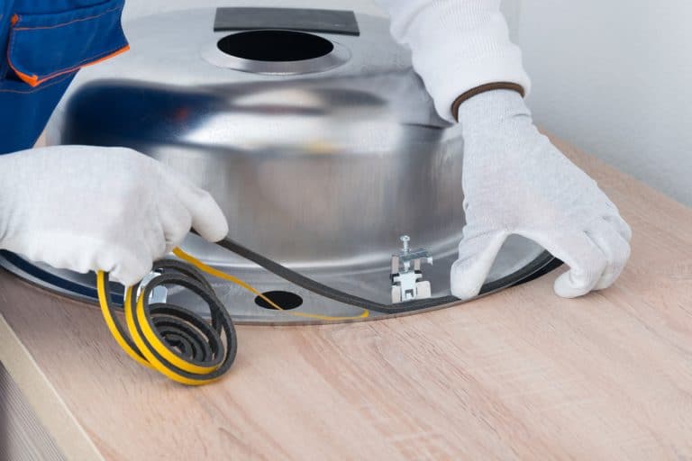 a specialist in protective clothing, glues a sealing tape to eliminate moisture between the countertop and the metal sink, Should You Seal Bathroom Countertops?