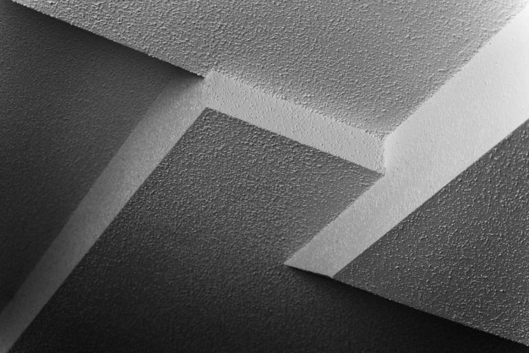 Abstract black and white image of intersection of four different popcorn ceiling panels at different heights, Does A Popcorn Ceiling Reduce Noise?